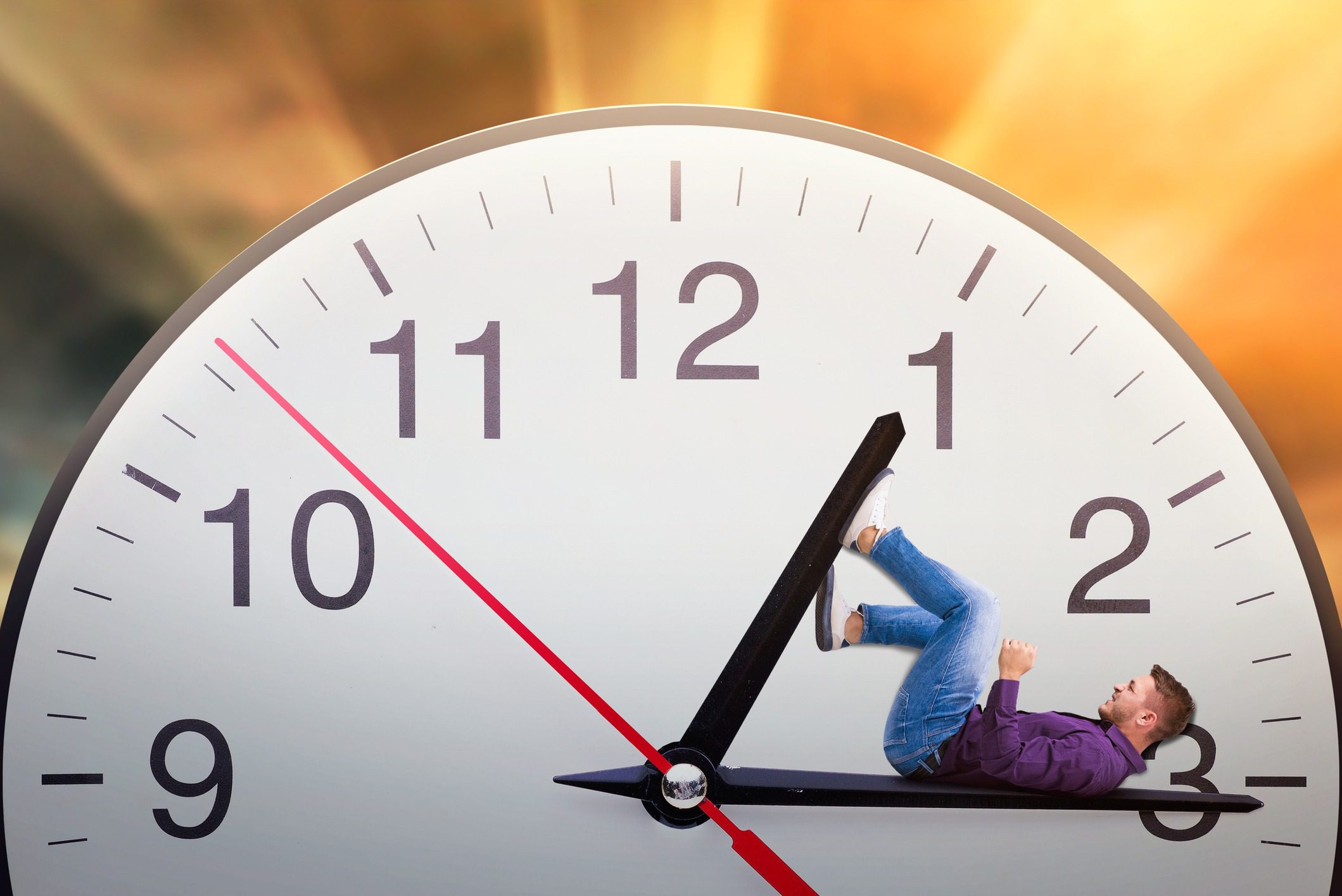 Man lies on the arrow of a huge clock and trying to stop time. Deadline concept